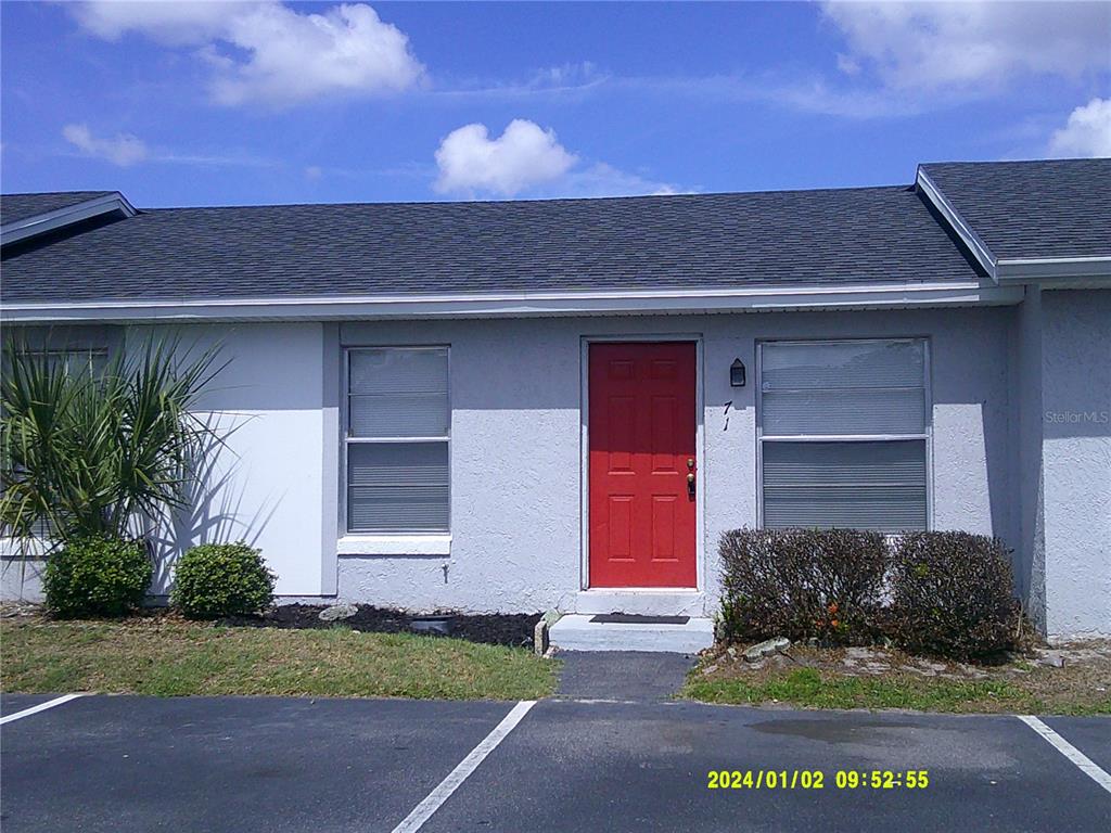 A single-story gray building features a bright red front door and two windows — 71 LAKE VILLA WAY, KISSIMMEE, FL