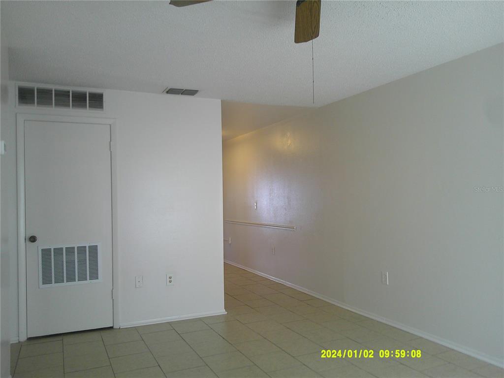 An interior view shows a room with tiled flooring, a white door, and a hallway — 71 LAKE VILLA WAY, KISSIMMEE, FL