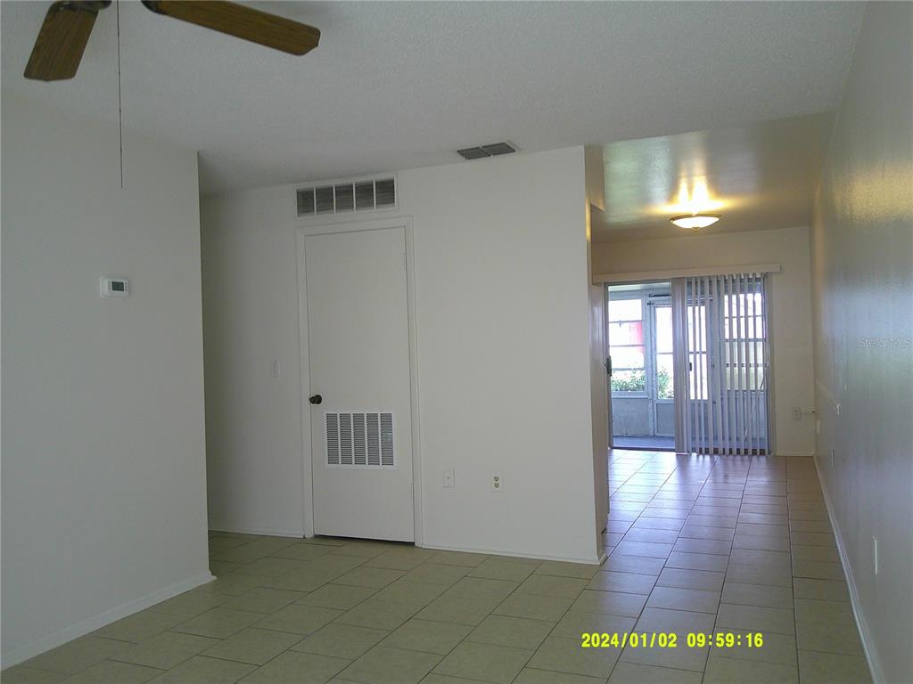 A living area with tile flooring leads to a sunroom through sliding glass doors — 71 LAKE VILLA WAY, KISSIMMEE, FL