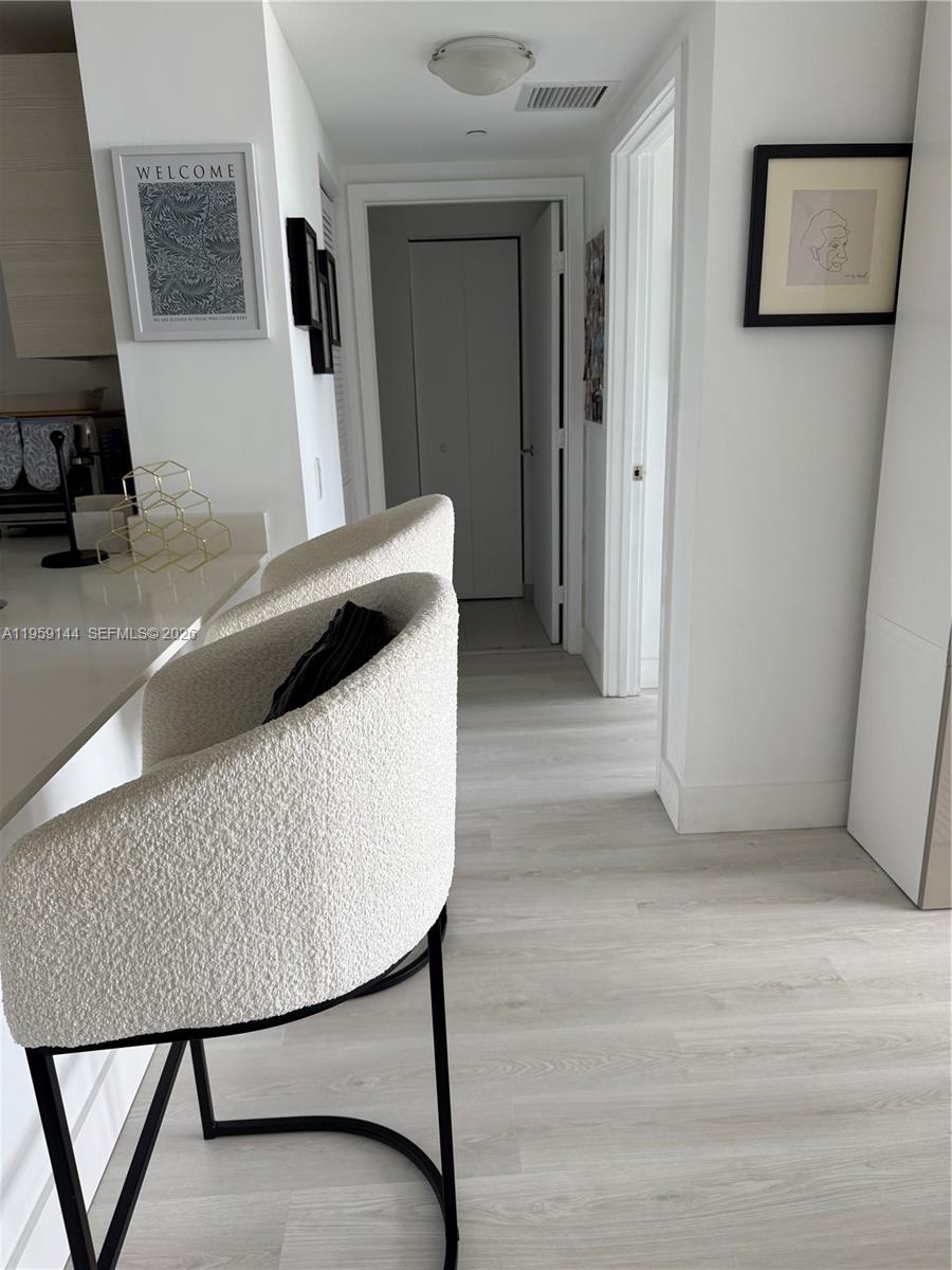 A kitchen counter with two textured bar stools leads into a hallway with light flooring — 4250 Biscayne Blvd # 1618, Miami FL 33137, MIAMI, FL