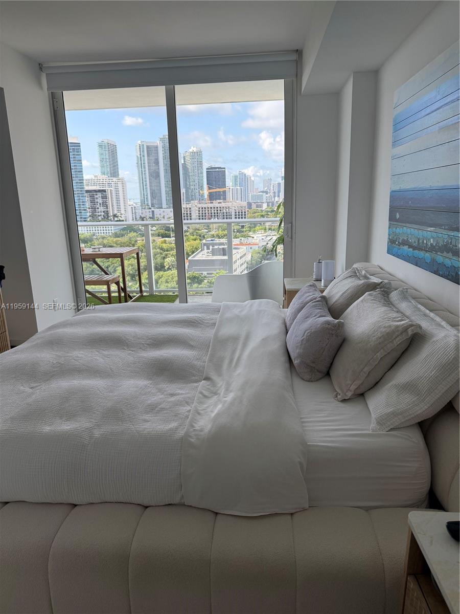 A bedroom features a bed with white bedding, a large window, and a city view — 4250 Biscayne Blvd # 1618, Miami FL 33137, MIAMI, FL