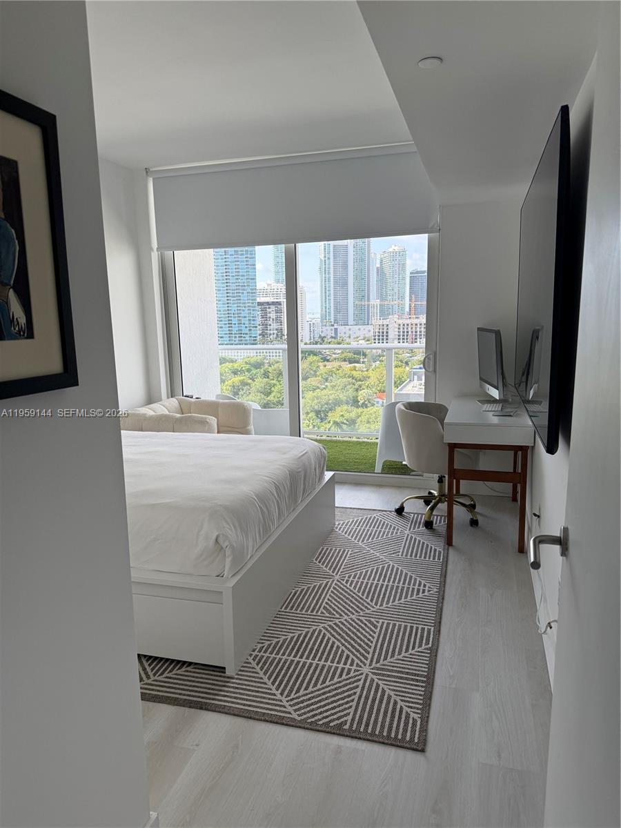 A bedroom features a bed, a desk, a geometric rug, and a balcony with city views — 4250 Biscayne Blvd # 1618, Miami FL 33137, MIAMI, FL