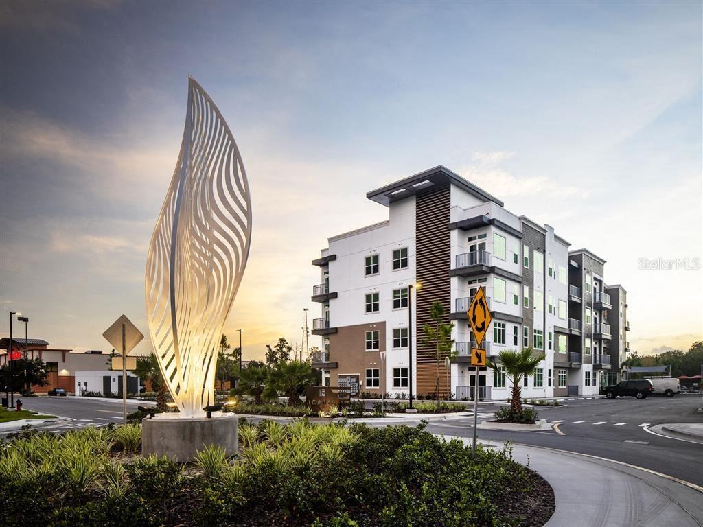 A large white abstract sculpture stands in front of a modern multi-story apartment building — 1185 S PINELLAS AVENUE UNIT A2, TARPON SPRINGS, FL