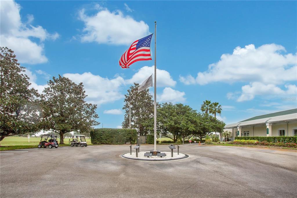 An American flag flies on a pole in a paved parking lot near a building — 842 OLD OAKS LANE, LEESBURG, FL