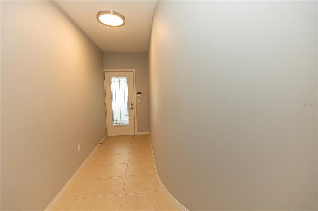 A tiled entryway features a light gray wall, a flush-mount ceiling light, and a front door — 9203 GRIGGS ROAD UNIT 102, ENGLEWOOD, FL