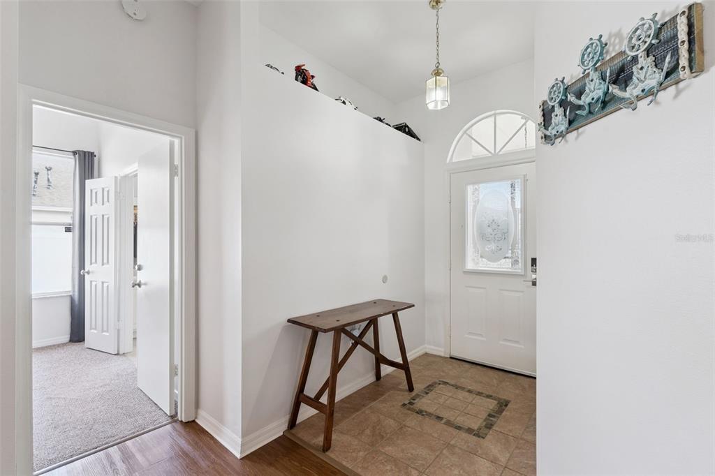 An entryway features a tiled floor, a wooden console table, and a white front door — 14825 GREATER PINES BOULEVARD, CLERMONT, FL