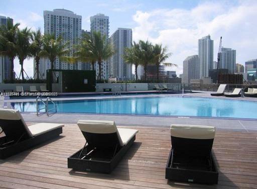 A swimming pool with lounge chairs on a wooden deck overlooking a city skyline — 90 SW 3rd St # 3708, Miami FL 33130, MIAMI, FL