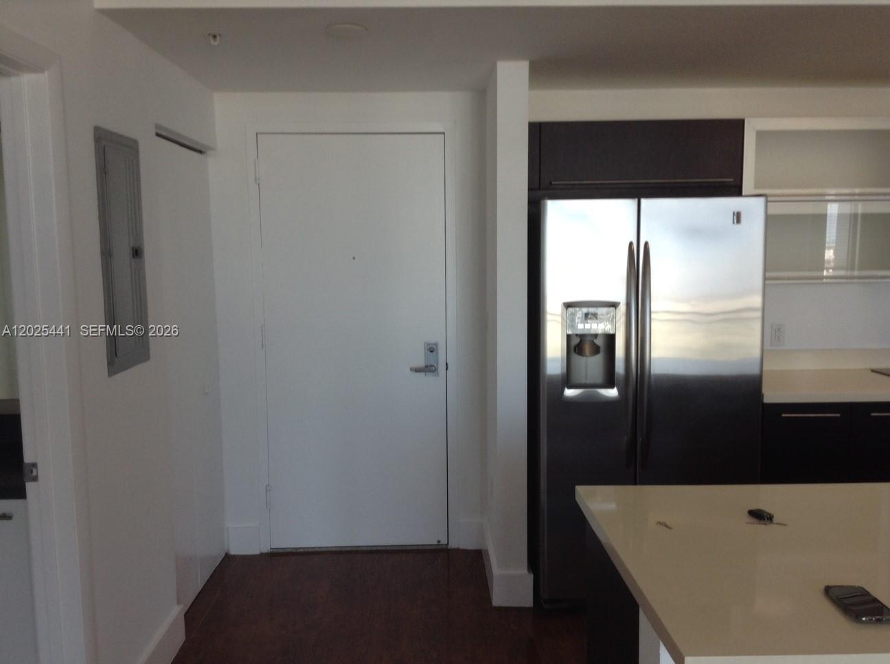 A kitchen area features a stainless steel refrigerator, white door, and dark wood flooring — 90 SW 3rd St # 3708, Miami FL 33130, MIAMI, FL