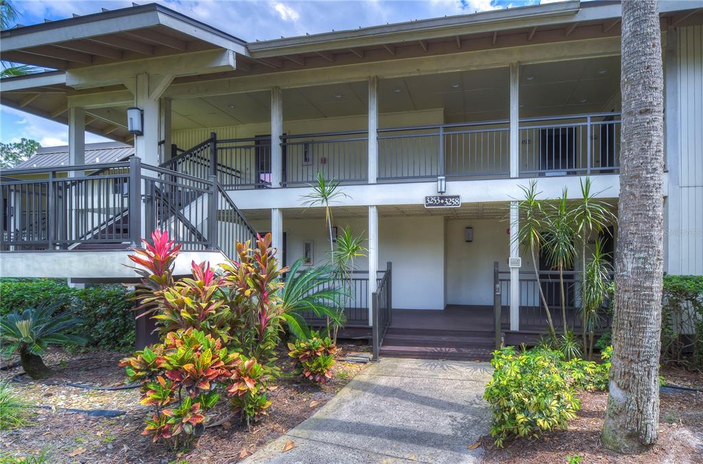 A two-story apartment building exterior features a covered walkway, metal railings, and tropical landscaping — 29300 BAY HOLLOW DRIVE UNIT 3256, WESLEY CHAPEL, FL