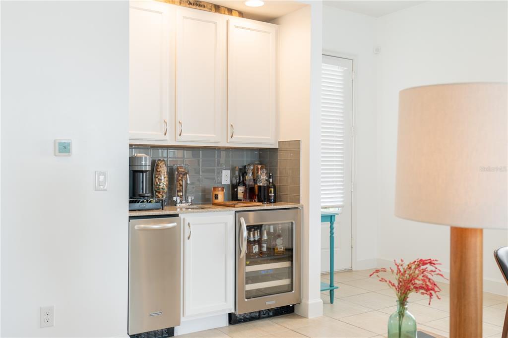 A wet bar features white cabinets, a stainless steel beverage cooler, and a gray tiled backsplash — 1545 FAIRVIEW CIRCLE, REUNION, FL