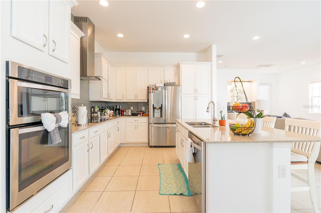 A bright kitchen features white cabinetry, stainless steel appliances, a center island, and tile flooring — 1545 FAIRVIEW CIRCLE, REUNION, FL
