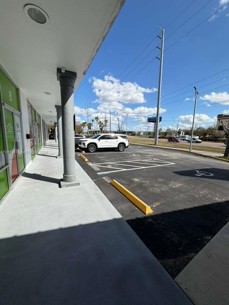 A view from a covered walkway looking out toward a parking lot and road — 2003 MCCOY RD # D, Orlando FL 32809, ORLANDO, FL