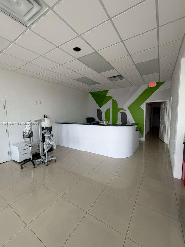 A reception area features a curved white desk, tiled floors, and a green wall graphic — 2003 MCCOY RD # D, Orlando FL 32809, ORLANDO, FL