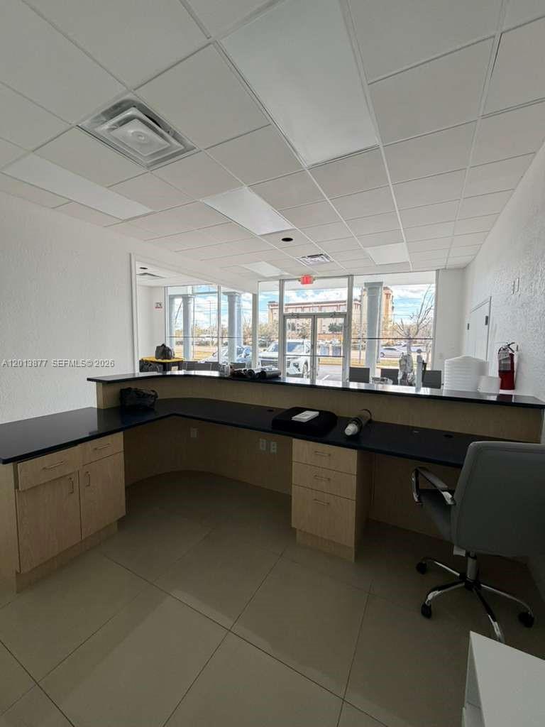 A reception area features a large L-shaped desk with light wood cabinets and black countertops — 2003 MCCOY RD # D, Orlando FL 32809, ORLANDO, FL
