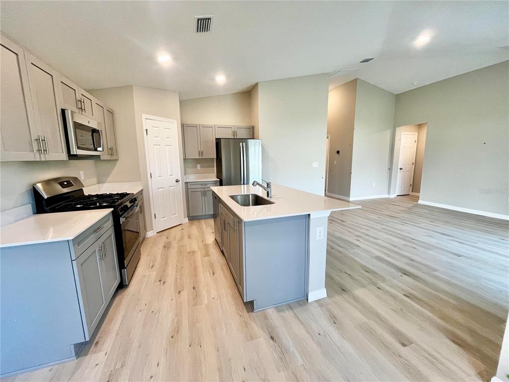 A kitchen with gray cabinets, stainless steel appliances, and a central island with a sink — 14664 GALLOP RUN DRIVE, LITHIA, FL