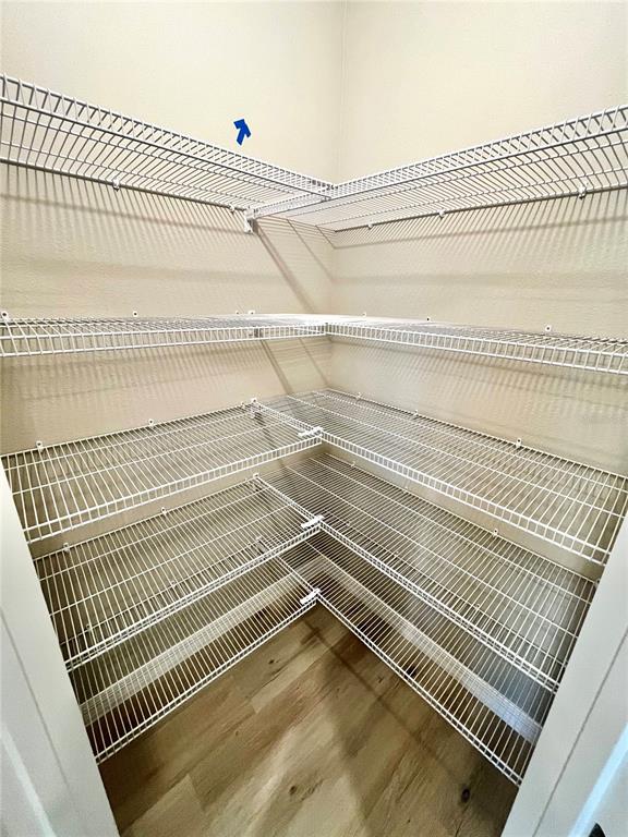 A walk-in pantry features white wire shelving units installed along the walls above wood-look flooring — 14664 GALLOP RUN DRIVE, LITHIA, FL