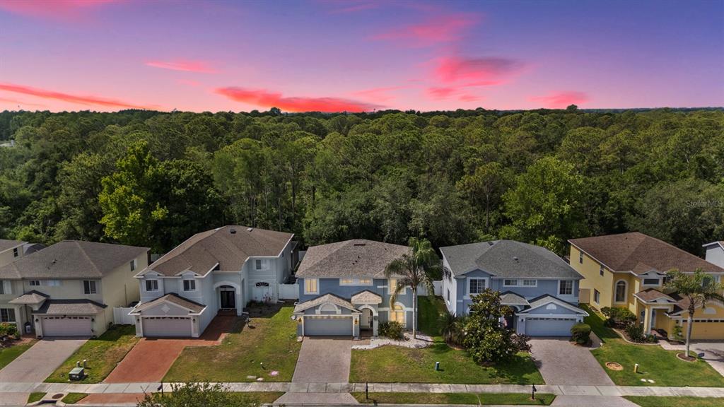 An aerial view of four suburban houses with driveways in front of a dense forest — 380 ROSALIND LANE, OLDSMAR, FL