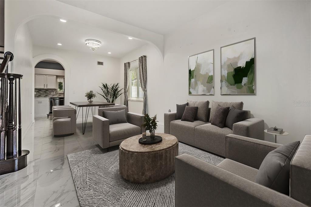A living room with gray furniture, a marble coffee table, and a dining area beyond — 380 ROSALIND LANE, OLDSMAR, FL