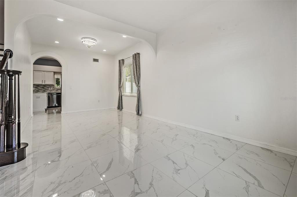 A bright room with white marble-look tile flooring and an arched entryway to a kitchen — 380 ROSALIND LANE, OLDSMAR, FL