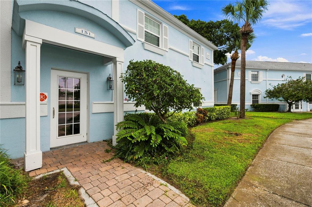 A light blue building exterior features a white-framed entrance, brick walkway, and palm trees — 151 SEAHORSE DRIVE SE UNIT B, ST PETERSBURG, FL