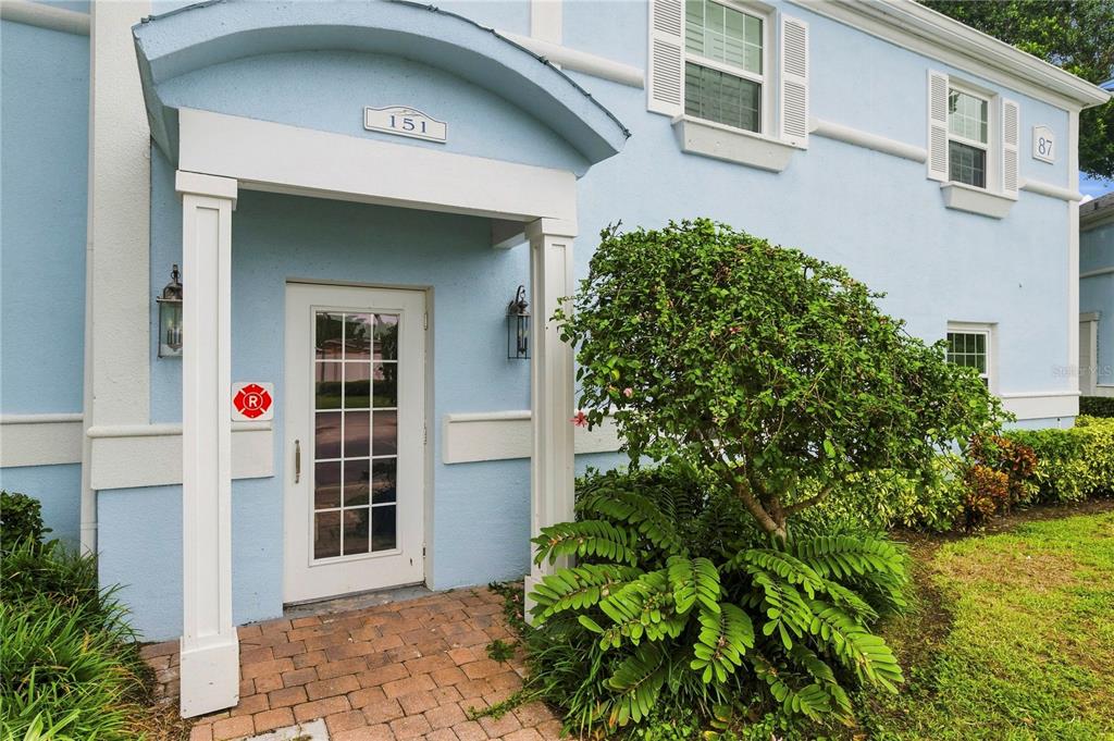 The exterior of a light blue building features a covered entryway with a glass door — 151 SEAHORSE DRIVE SE UNIT B, ST PETERSBURG, FL