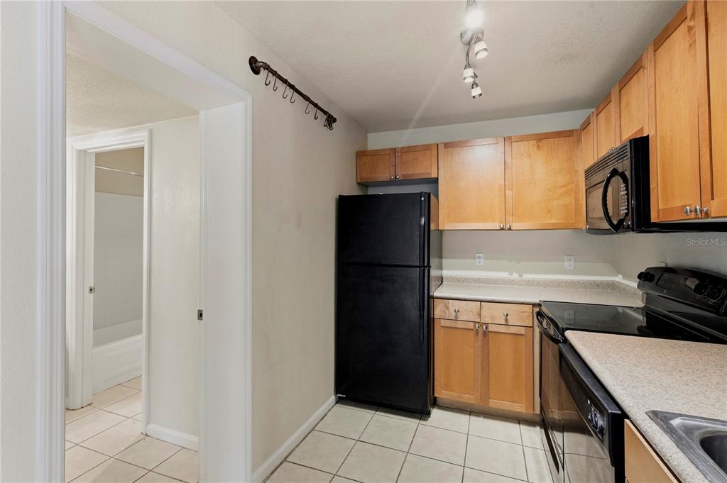 A kitchen features light wood cabinets, black appliances, and white tile flooring — 151 SEAHORSE DRIVE SE UNIT B, ST PETERSBURG, FL