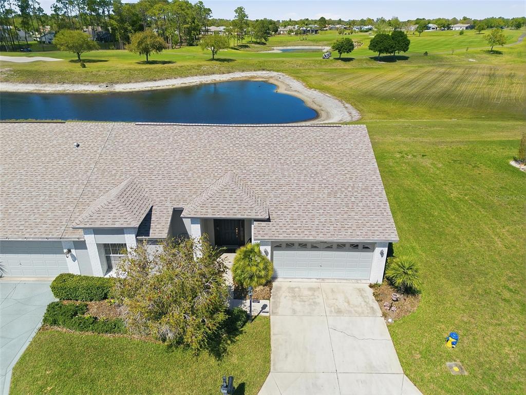 An aerial view shows a single-story house with a gray roof, garage, and concrete driveway — 11131 HOLLANDER AVENUE, HUDSON, FL