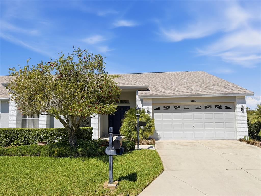 A single-story house with a white brick facade, a two-car garage, and a front lawn — 11131 HOLLANDER AVENUE, HUDSON, FL