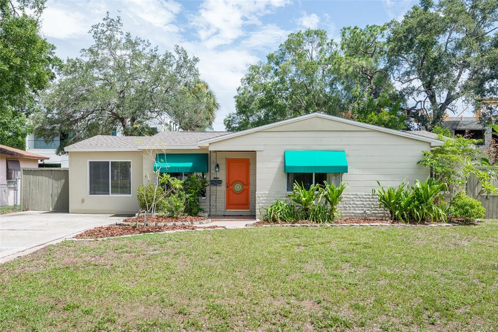 A single-story house with light siding, an orange front door, and turquoise window awnings — 4425 W BAY VILLA AVENUE, TAMPA, FL