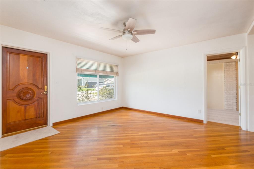An empty room with hardwood floors, a ceiling fan, a window, and a wooden door — 4425 W BAY VILLA AVENUE, TAMPA, FL