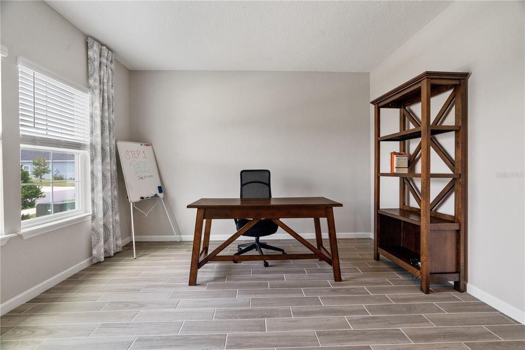 A home office features a wooden desk, a black chair, a bookshelf, and tile flooring — 9324 SW 58TH CIRCLE, OCALA, FL