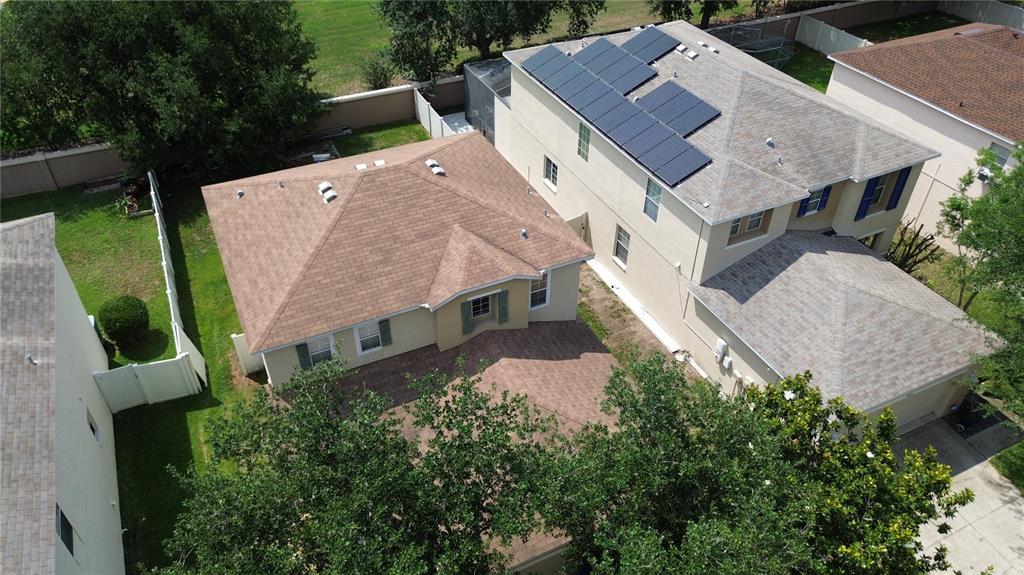 An aerial view shows two adjacent suburban houses with shingled roofs and a fenced yard — 9631 SIMEON DRIVE, LAND O LAKES, FL
