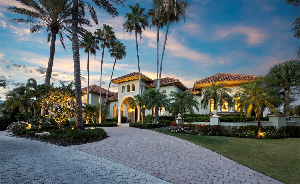 A large Mediterranean-style house with a paved driveway and palm trees at dusk — 1280 HIDDEN HARBOR WAY, SARASOTA, FL