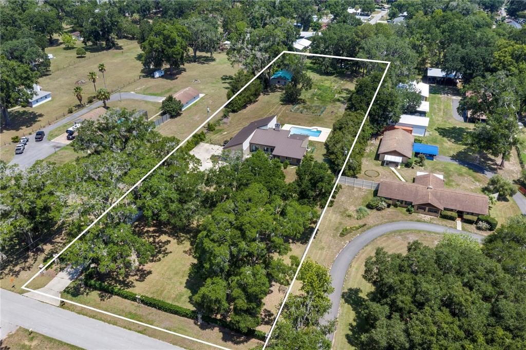 A single-story house with a metal roof and tan stucco exterior sits behind a lawn — 3261 SE 41ST PLACE, OCALA, FL