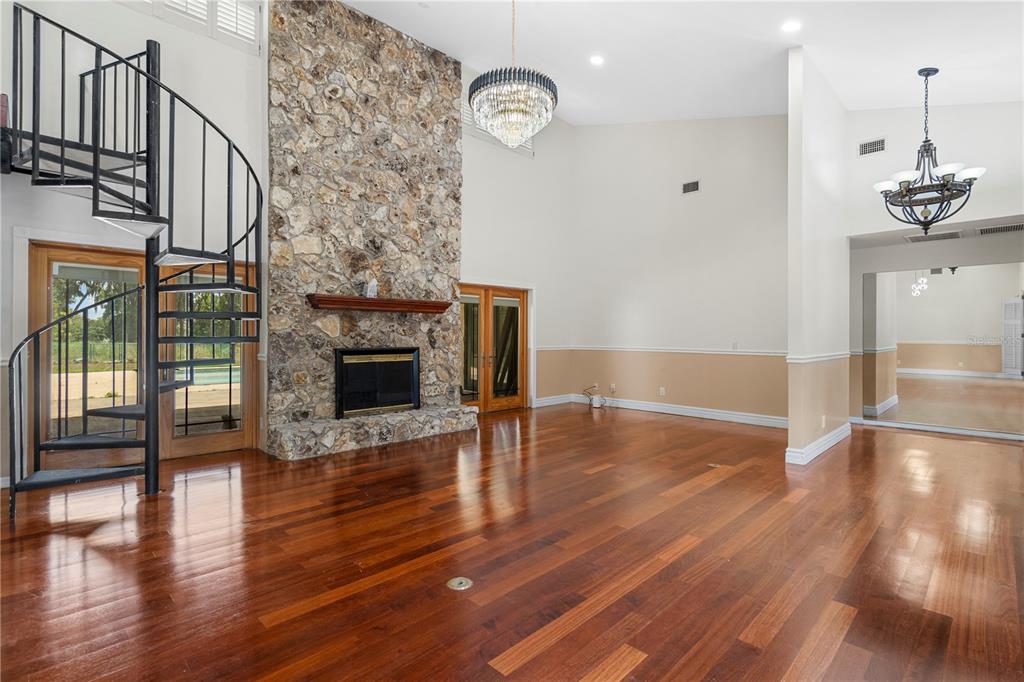 A spacious living room features hardwood floors, a stone fireplace, and a black spiral staircase — 3261 SE 41ST PLACE, OCALA, FL