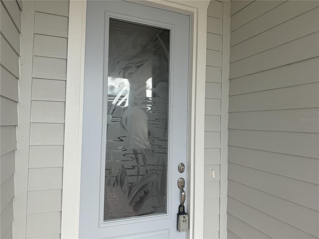 A light blue front door features an etched glass panel depicting a bird in reeds — 6 BLUE GROTTO PLACE, PALM COAST, FL