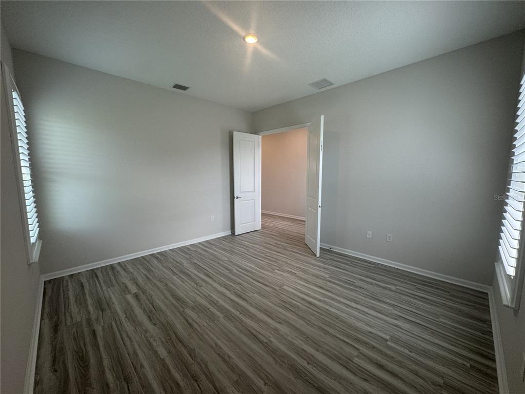 An empty room with light gray walls, wood-look flooring, and two windows with white blinds — 6 BLUE GROTTO PLACE, PALM COAST, FL