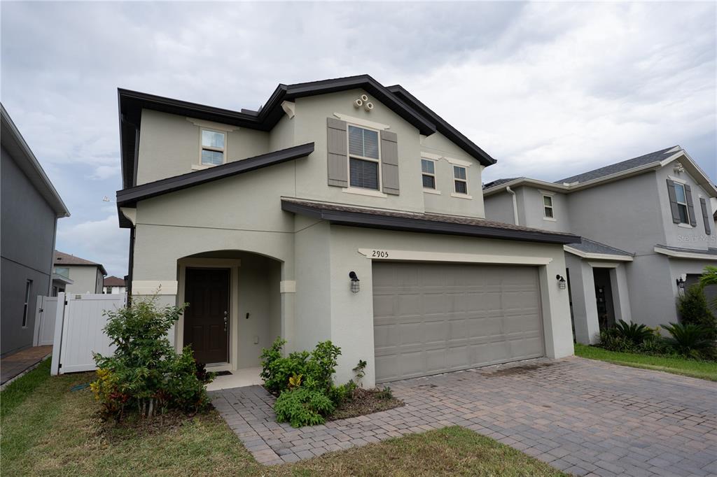 A two-story house with a beige stucco exterior, a two-car garage, and a paved driveway — 2905 SUMMER GREEN TRAIL, KISSIMMEE, FL