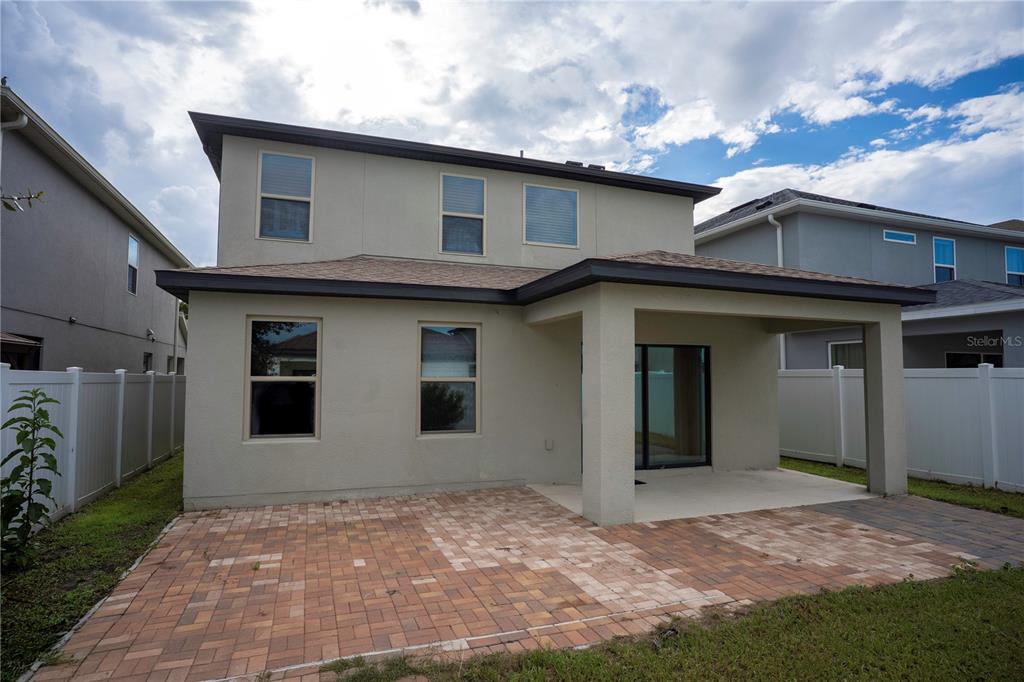 The exterior rear view of a two-story house features a paved patio and covered porch — 2905 SUMMER GREEN TRAIL, KISSIMMEE, FL