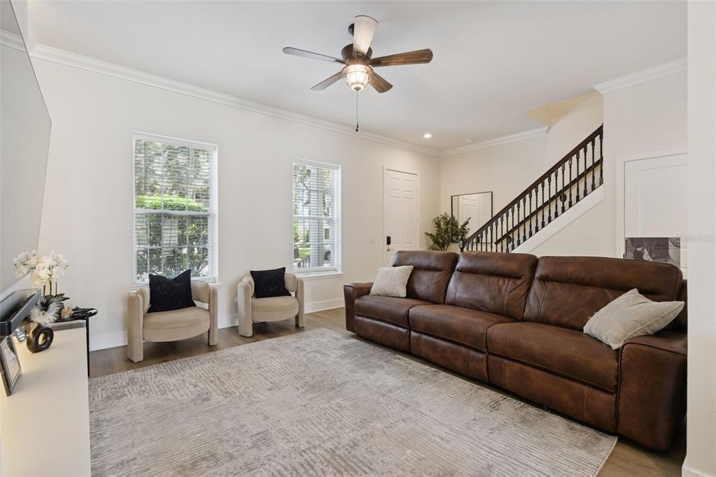 A living room features a brown leather sofa, two armchairs, and a staircase — 1134 CELEBRATION AVENUE, CELEBRATION, FL