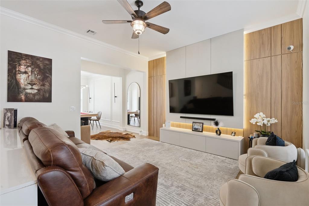 A living room features a leather sofa, two armchairs, and a wall-mounted television with cabinetry — 1134 CELEBRATION AVENUE, CELEBRATION, FL