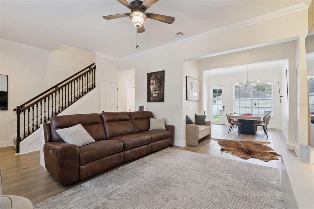 A living room with a brown leather sofa, staircase, and an adjacent dining area — 1134 CELEBRATION AVENUE, CELEBRATION, FL