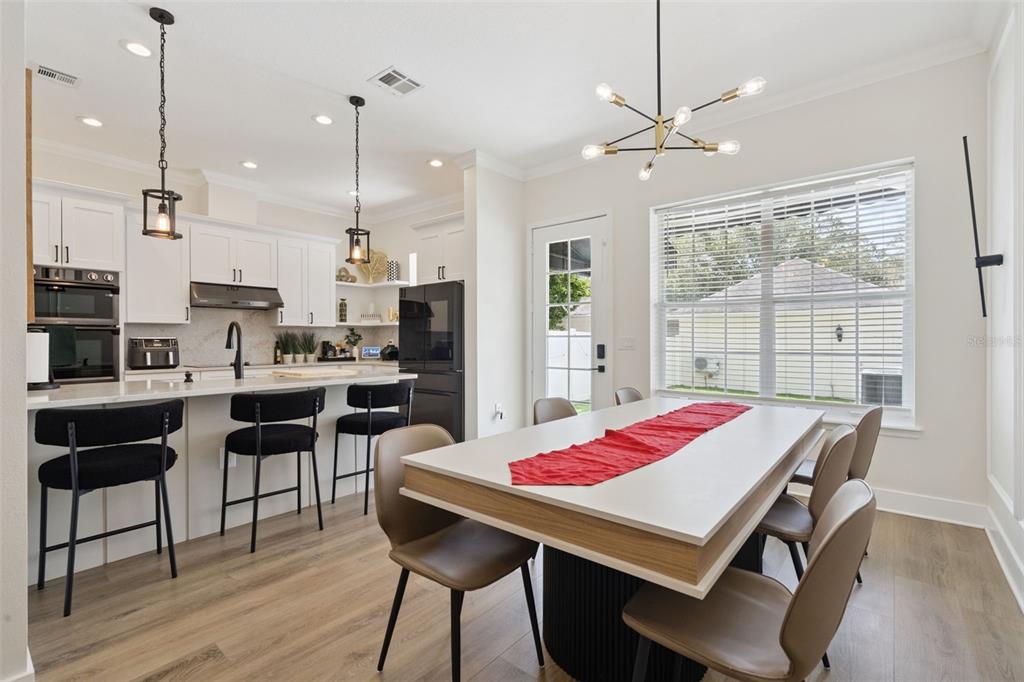 A kitchen with white cabinets and a dining area featuring a modern light fixture — 1134 CELEBRATION AVENUE, CELEBRATION, FL