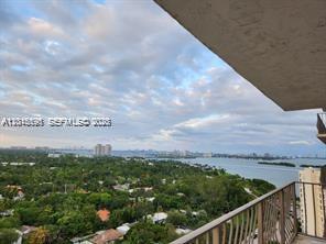 A high-angle view from a balcony overlooking a lush green landscape and a large bay — 780 NE 69th St # 1810, Miami FL 33138, MIAMI, FL