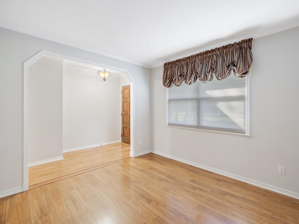 An empty room with light wood floors, gray walls, and an arched entryway to another space — 4790 16th Street, Vero Beach FL 32966, VERO BEACH, FL