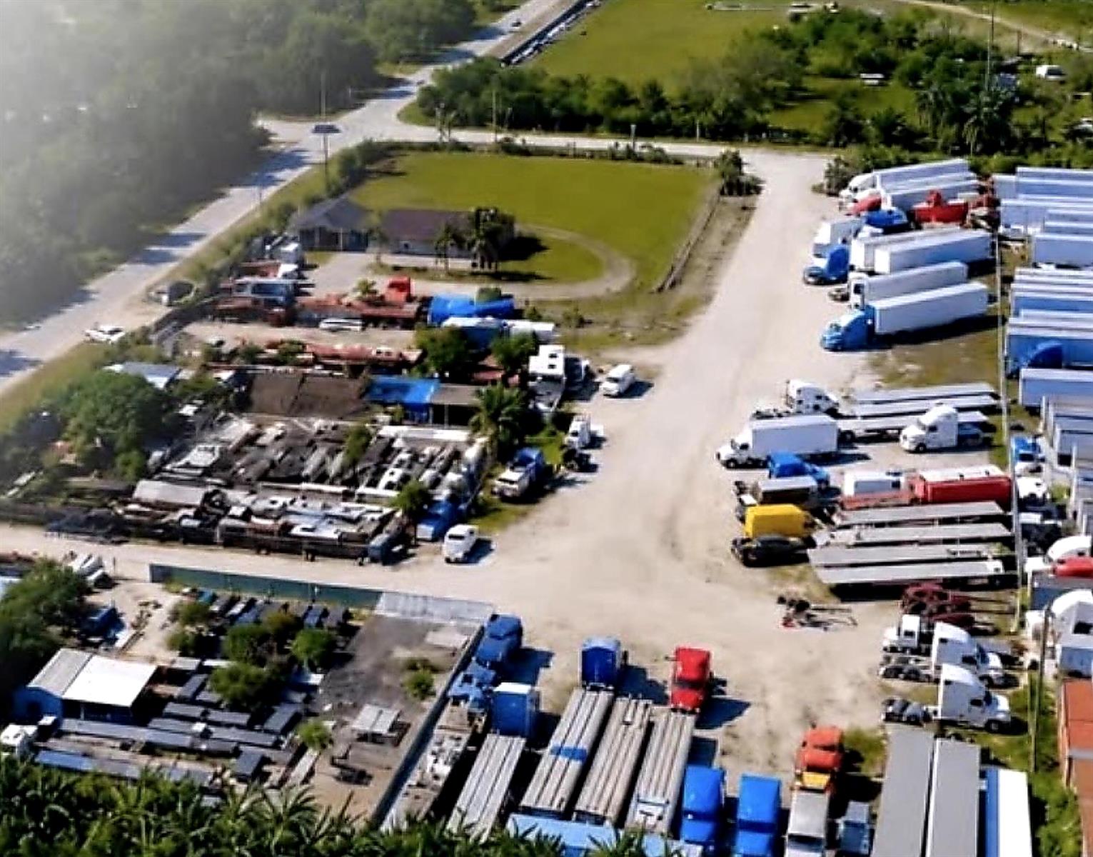 An aerial view shows a commercial truck parking lot with numerous trailers and semi-trucks — MIAMI, FL