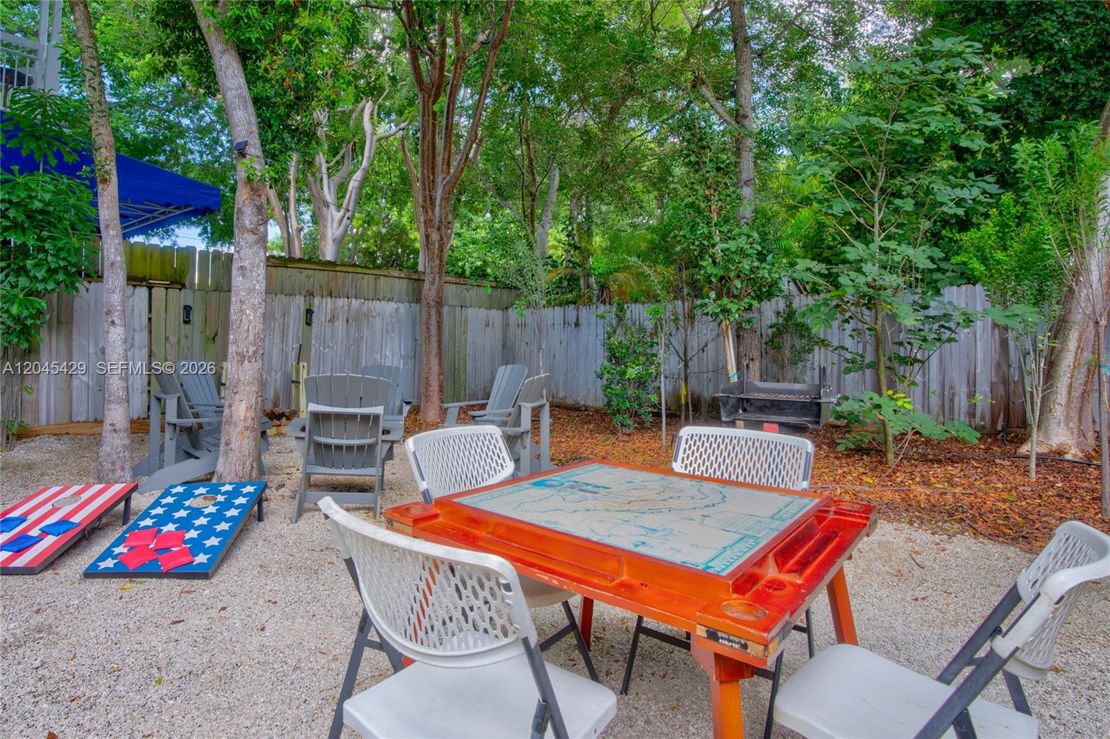 A backyard patio features a game table, chairs, cornhole boards, and a charcoal grill — 27 Blue Runner St, Key Largo FL 33037, KEY LARGO, FL