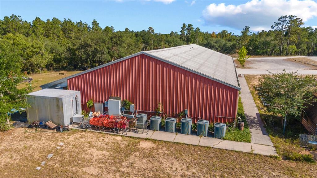 An exterior view of a red metal building with several air conditioning units and shopping carts — 6491 & 6481 SE 123RD TERRACE, MORRISTON, FL