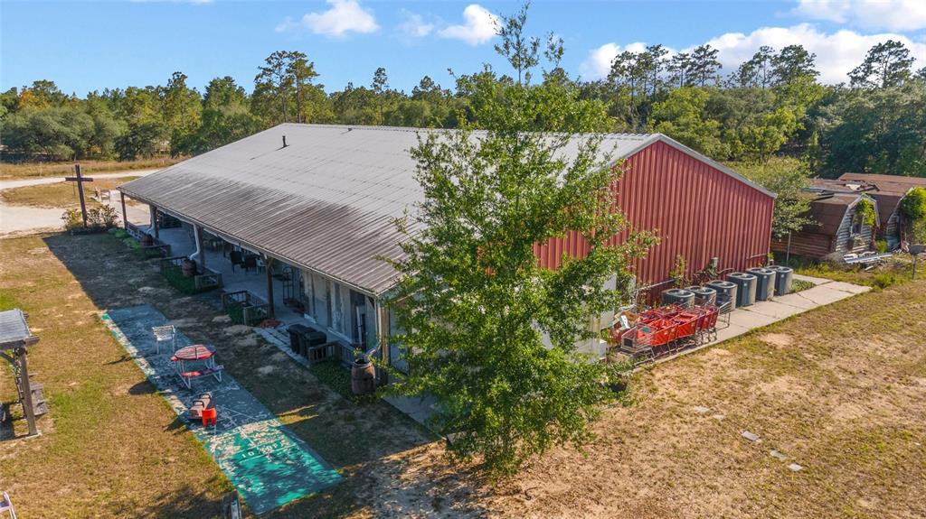 An aerial view shows a red metal building with a large porch and surrounding grounds — 6491 & 6481 SE 123RD TERRACE, MORRISTON, FL