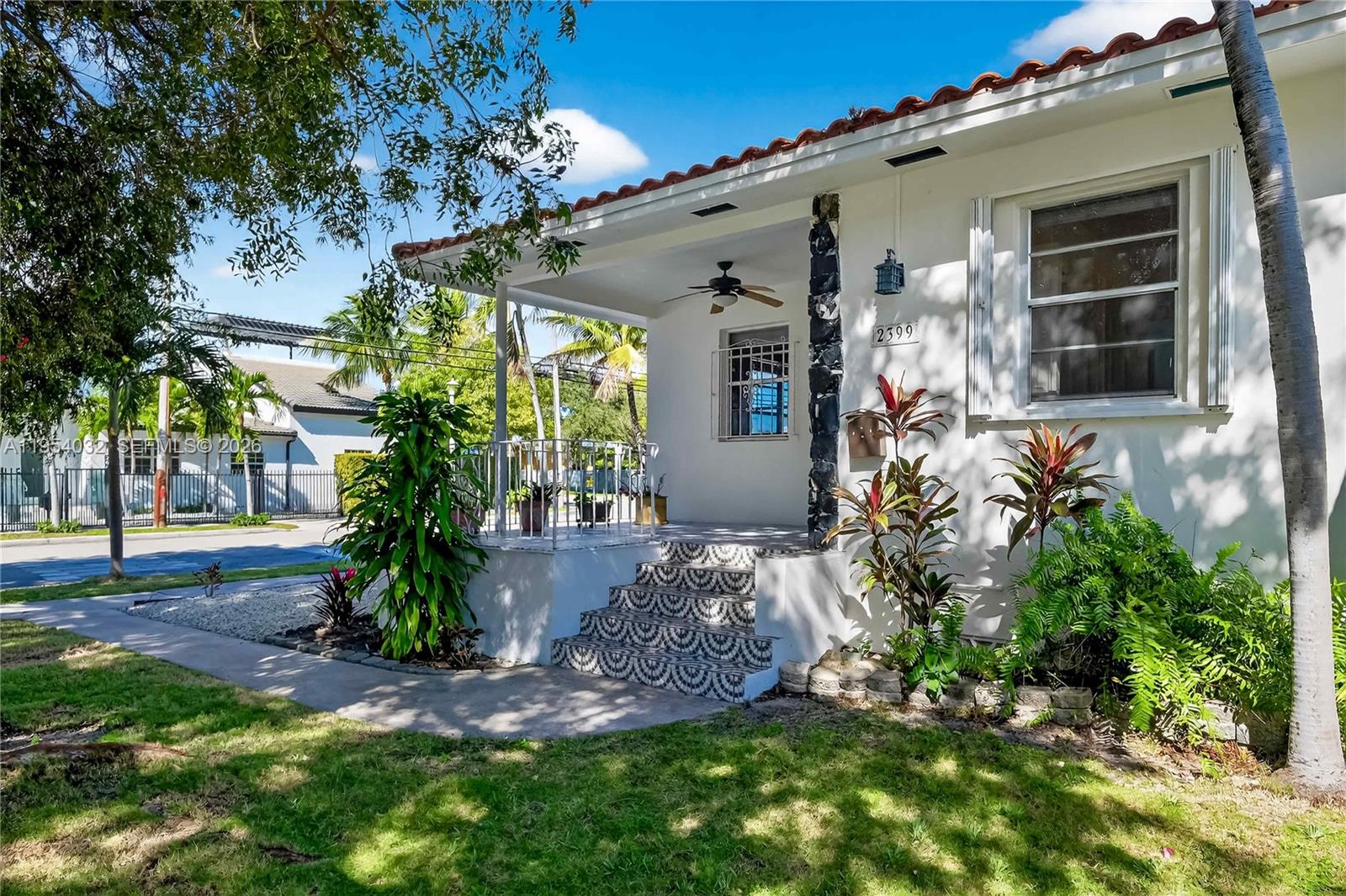 A white house features a covered front porch with patterned tile steps and landscaping — 2399 SW 26th Ln, Miami FL 33133, MIAMI, FL